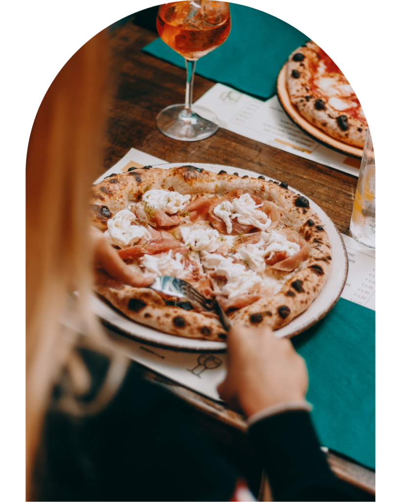 persona che taglia una pizza con forchetta e coltello